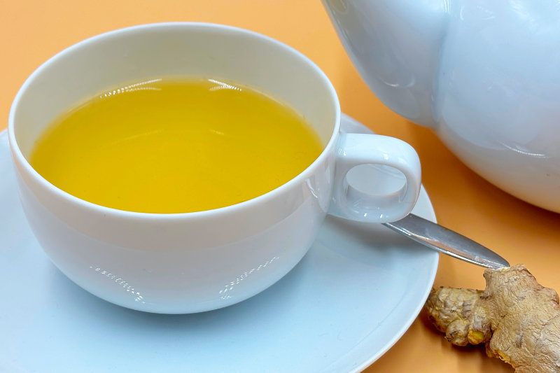 Eine Tasse Tee mit Ingwerwurzel daneben