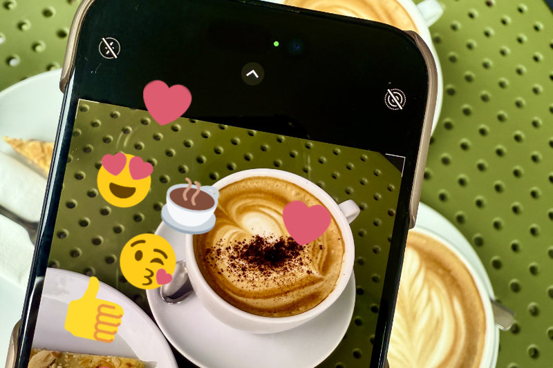 Bild zeigt den Ausschnitt eines Handys, mit dem gerade ein Kaffee fotografiert wird. Auf dem Bildschirm sind noch Emojis zu sehen.